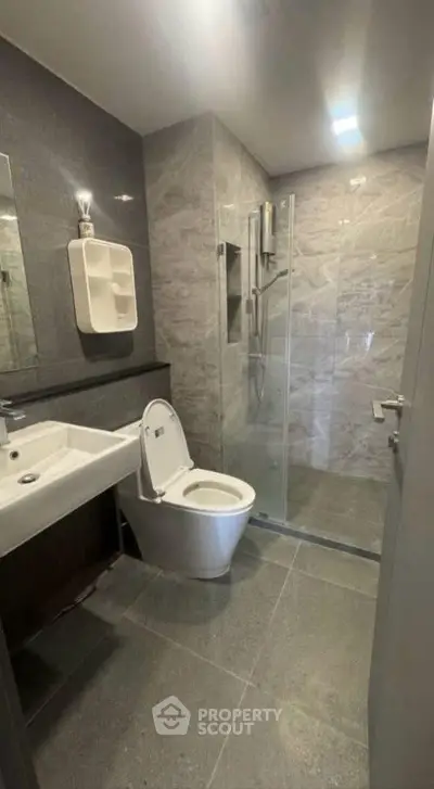 Modern bathroom with sleek design, featuring a glass shower and contemporary fixtures.