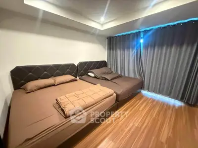 Spacious bedroom with two large beds and elegant wooden flooring.