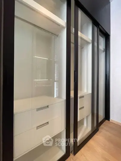 Spacious walk-in closet with sleek sliding glass doors and modern storage solutions.