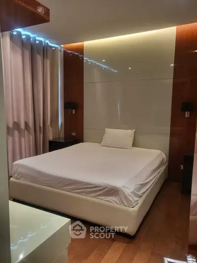 Luxurious bedroom with modern design and ambient lighting, featuring a comfortable bed and elegant wooden flooring.