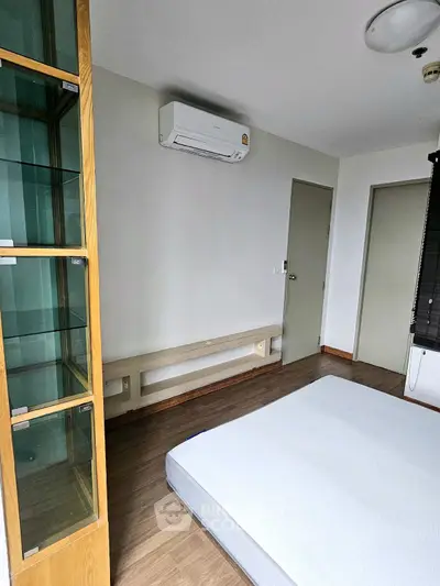 Spacious bedroom with air conditioning and wooden flooring, featuring a modern minimalist design.