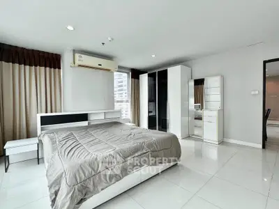 Spacious modern bedroom with sleek furniture and large windows in a high-rise apartment.