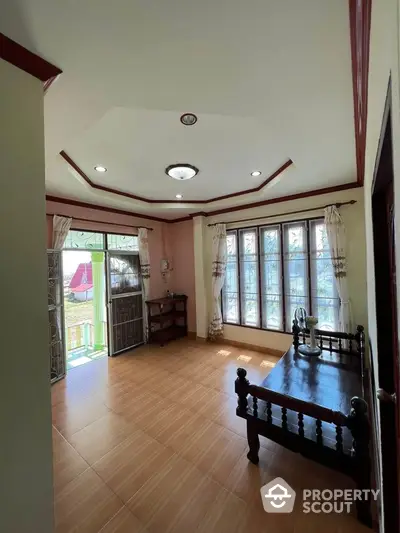 Charming living room with wooden furniture and large windows offering natural light.