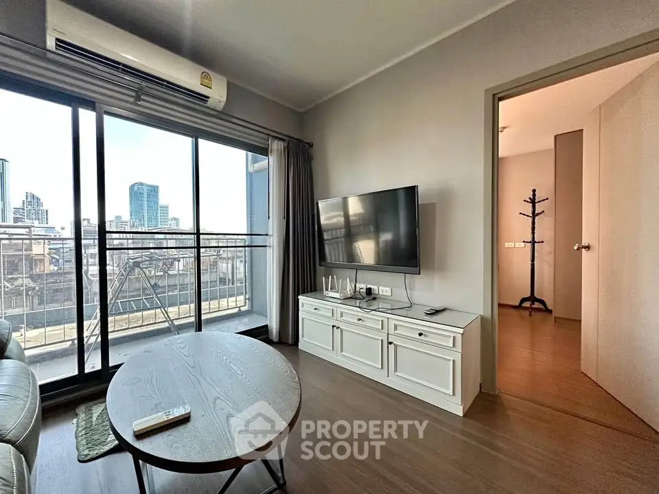 Modern living room with city view, featuring sleek furniture and large windows for natural light.