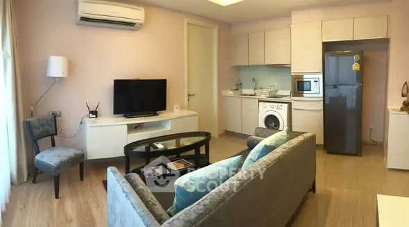 Modern living room with open kitchen, featuring sleek appliances and cozy seating area.