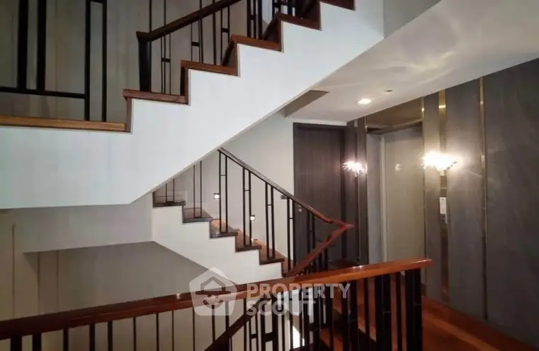 Elegant staircase with modern design and wooden railings in a luxurious building interior.