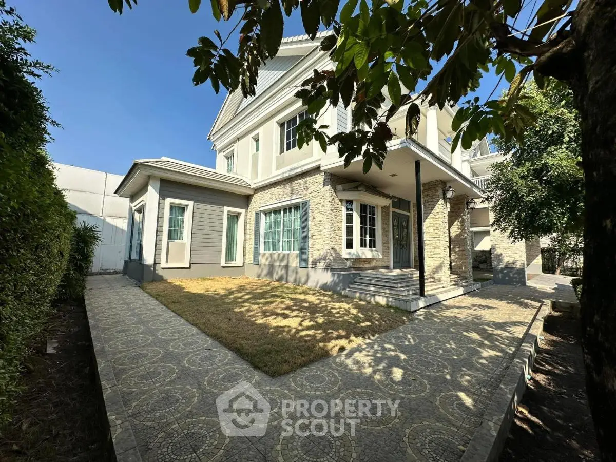 Charming two-story house with stone facade and lush garden, perfect for family living.