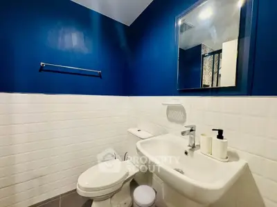 Modern bathroom with blue and white tiles, sleek sink, and mirror.