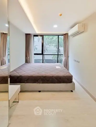 Modern bedroom with large window and air conditioning in a stylish apartment.
