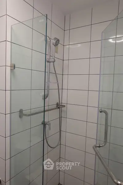 Modern bathroom with glass shower enclosure and tiled walls.