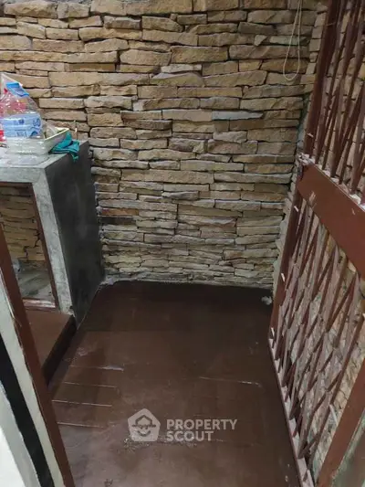 Cozy corner with rustic stone walls and secure metal gate, perfect for storage or small utility space.