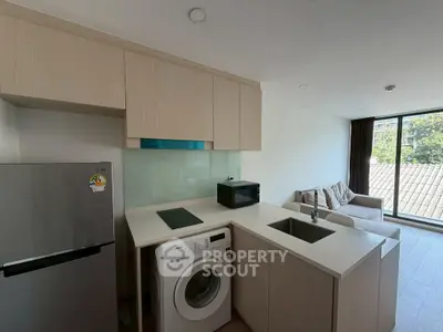 Modern kitchen with washing machine and cozy living area in open layout apartment