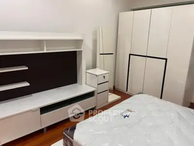 Modern bedroom with sleek white furniture and wooden flooring