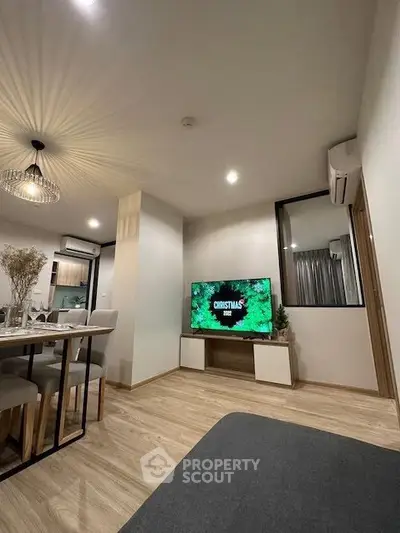 Modern living room with stylish decor and open layout, featuring a cozy dining area and sleek TV setup.