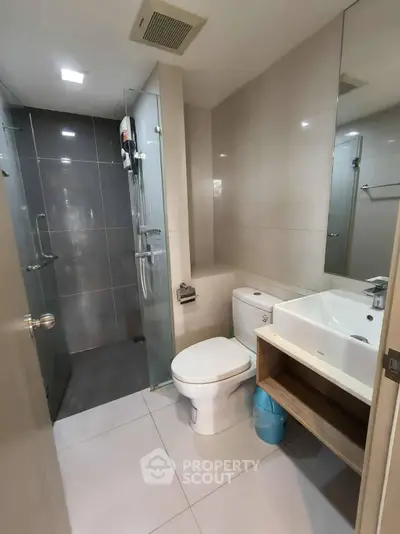 Modern bathroom with glass shower and sleek fixtures in contemporary apartment.