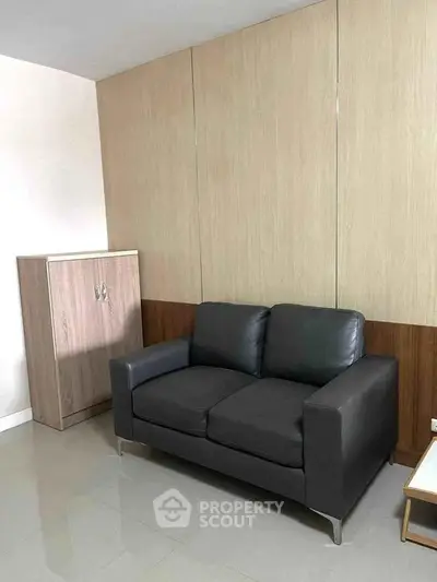 Modern living room with sleek black sofa and stylish wooden cabinet, perfect for contemporary urban living.