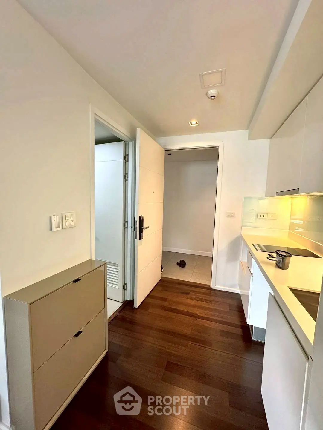 Modern apartment entrance with sleek kitchen and wooden flooring