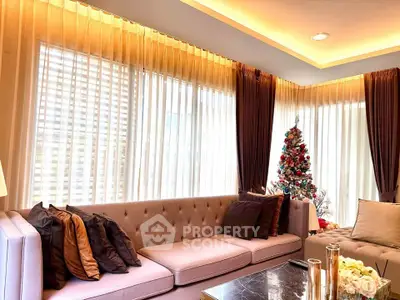 Elegant living room with plush sofa and Christmas tree, featuring warm lighting and stylish decor.