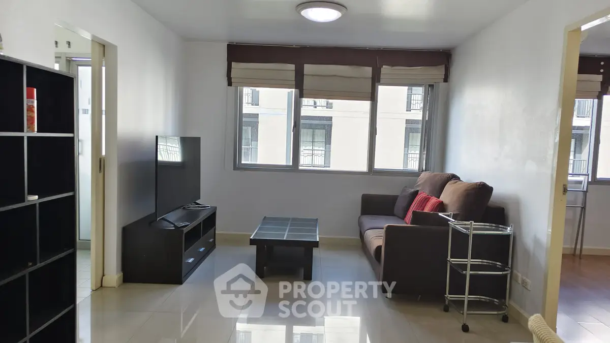 Modern living room with sleek furniture and large windows in a bright apartment.