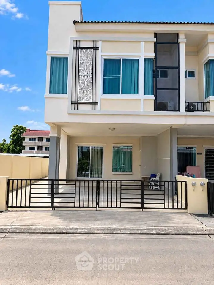 Modern two-story townhouse with sleek design and gated driveway in a suburban neighborhood.