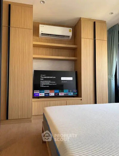 Modern bedroom with built-in wooden wardrobe and smart TV, featuring sleek air conditioning unit.