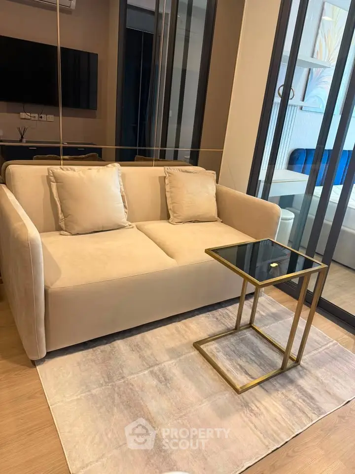 Modern living room with elegant beige sofa and glass-top side table in a stylish apartment.