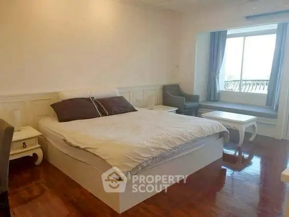 Spacious bedroom with elegant decor and large window offering natural light.