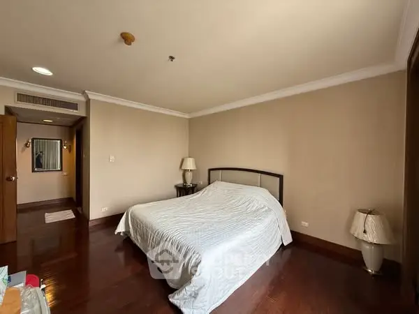 Spacious bedroom with elegant wooden flooring and cozy lighting