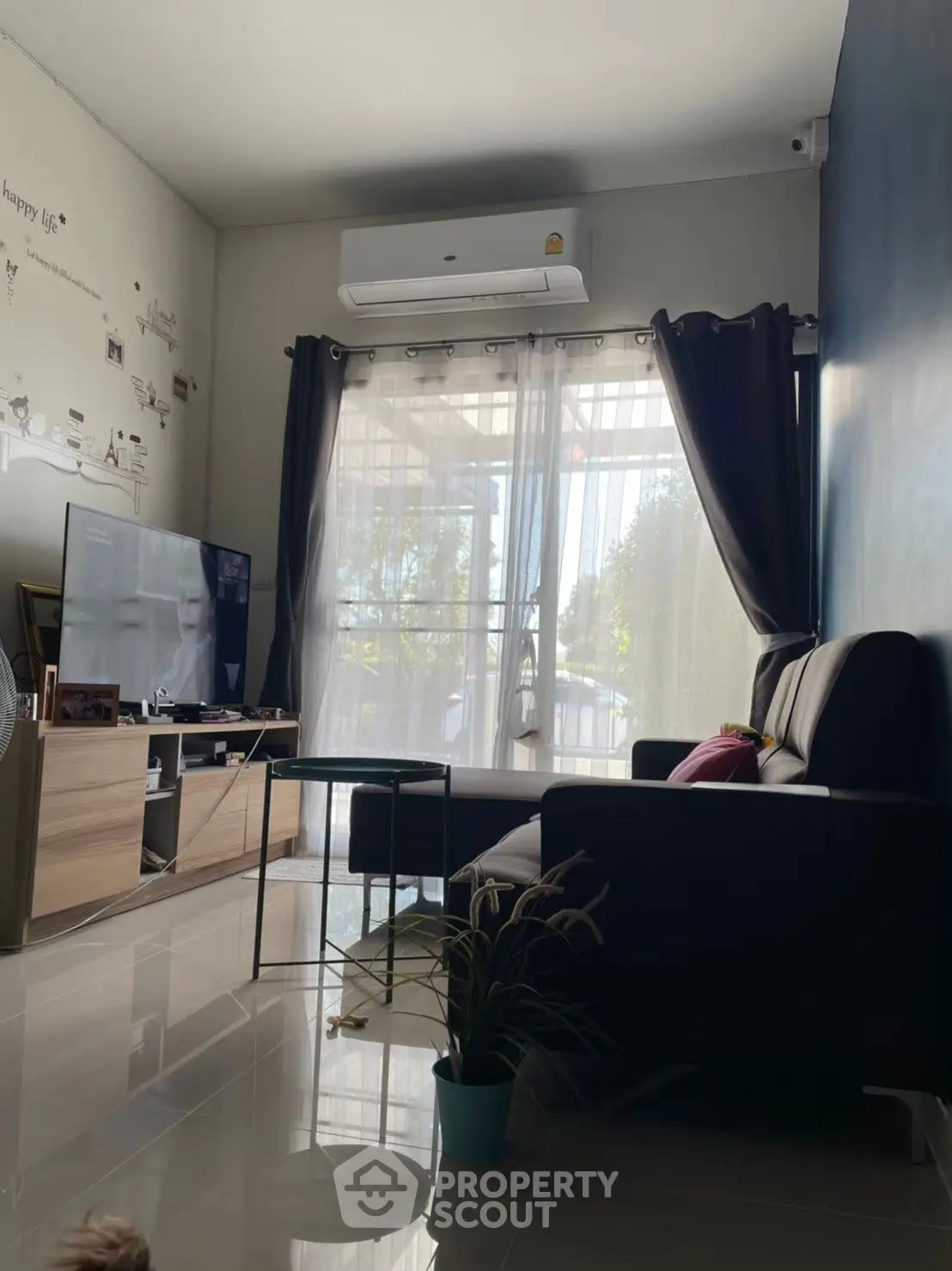 Cozy living room with modern decor and natural light, featuring a sleek sofa and entertainment setup.