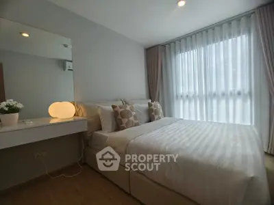 Cozy bedroom with elegant decor and natural light through sheer curtains.