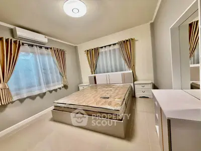Spacious bedroom with modern furnishings and ample natural light, featuring elegant curtains and a comfortable bed.