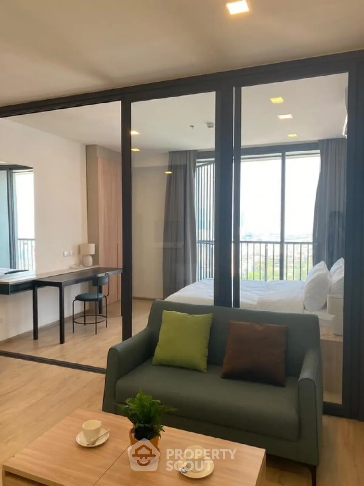 Modern apartment with glass partition, cozy living area, and bright bedroom with balcony view.
