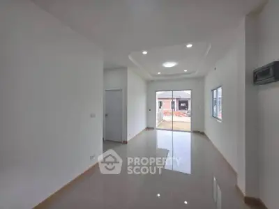 Spacious modern living room with glossy tiled floors and recessed lighting, featuring large windows for natural light.