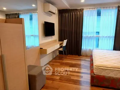 Modern bedroom with wooden flooring, wall-mounted TV, and large windows with curtains.