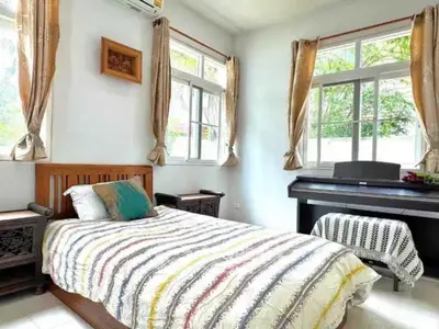 Charming bedroom with natural light and elegant decor, featuring a cozy bed and a stylish piano.