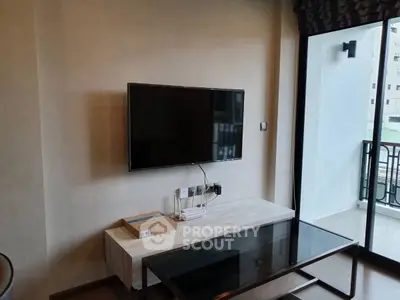 Modern living room with wall-mounted TV and glass coffee table near balcony.