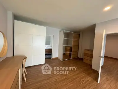 Spacious bedroom with modern wooden flooring and ample storage space