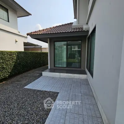 Modern house exterior with tiled patio and manicured hedge