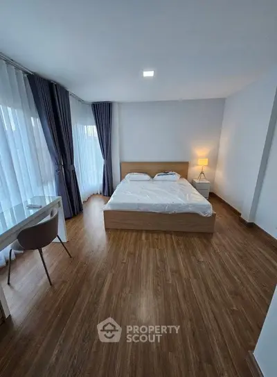 Spacious bedroom with modern decor and large windows for natural light