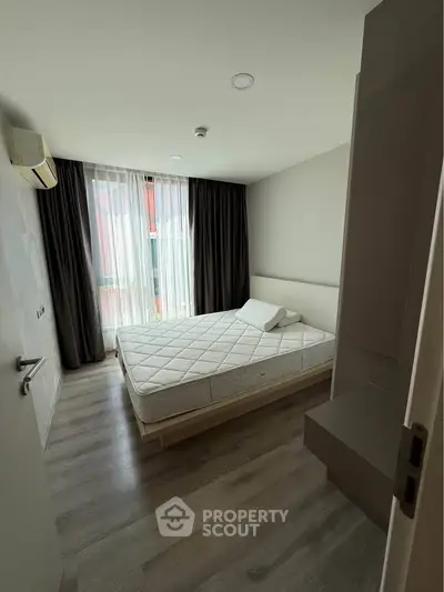 Modern bedroom with large window and minimalist decor, featuring a comfortable bed and sleek flooring.