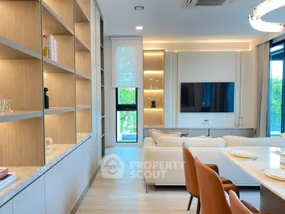 Modern living room with elegant shelving and large TV, featuring stylish furniture and natural light.