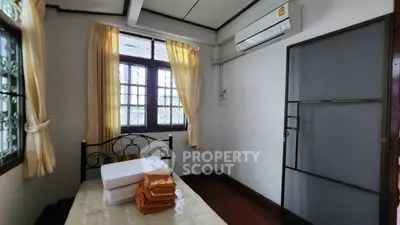 Cozy bedroom with air conditioning and natural light, featuring a comfortable bed and elegant curtains.