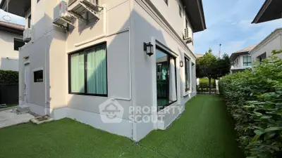 Modern residential building with lush green artificial lawn and large windows.