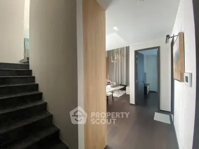 Modern interior hallway with staircase and stylish decor leading to a cozy living area.