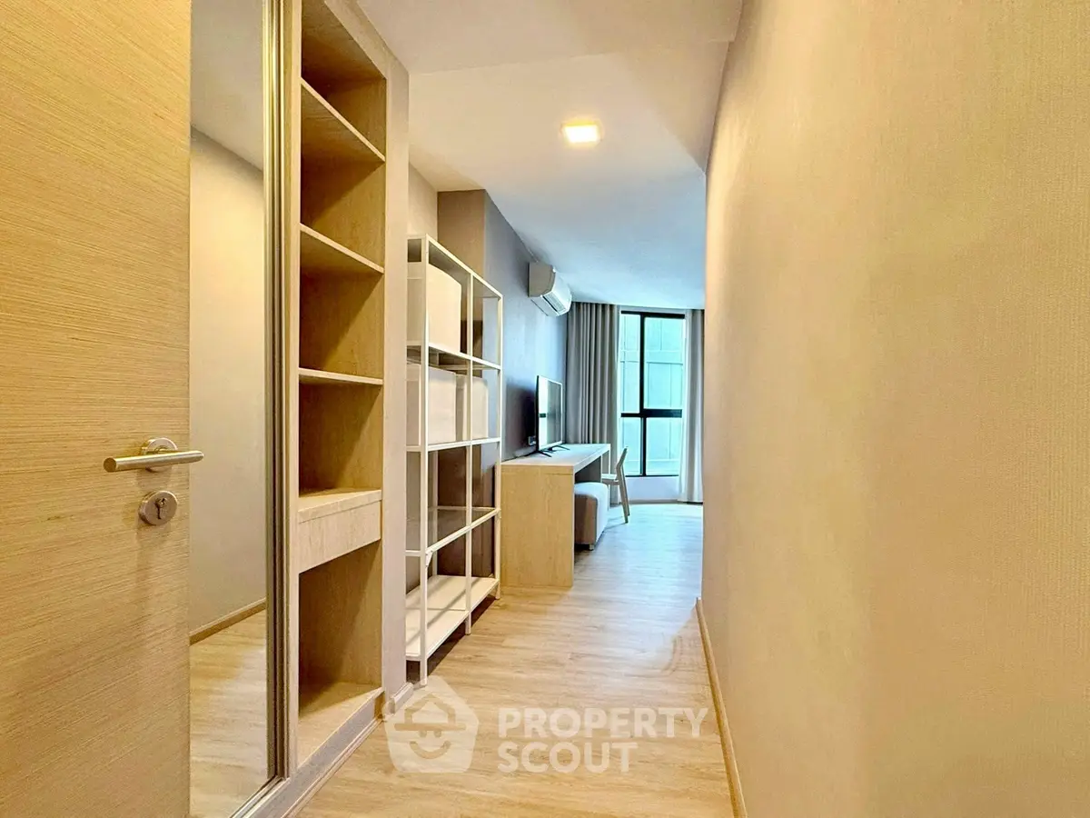 Modern apartment hallway with wooden flooring and built-in shelving