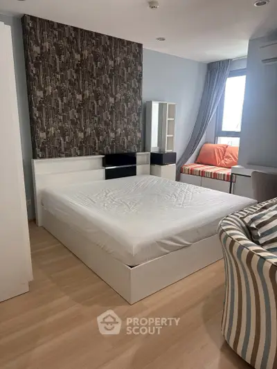 Modern bedroom with stylish decor and natural light, featuring a cozy bed and seating area.