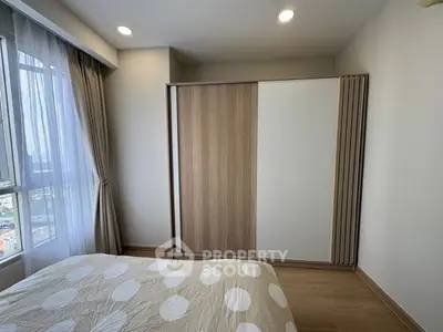 Modern bedroom with large window and stylish wardrobe, offering a cozy and bright living space.