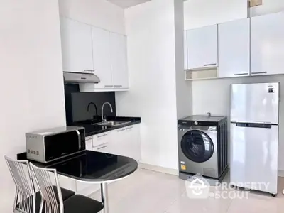 Sleek modern kitchen with high-end appliances, including a Samsung fridge and washing machine, complemented by white cabinetry and a cozy dining nook.