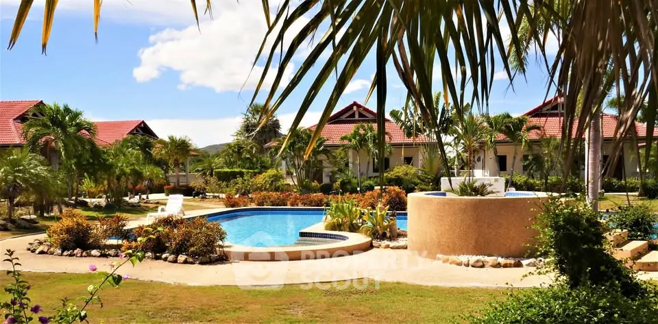 Luxurious tropical resort with stunning pool and lush gardens under a clear blue sky.