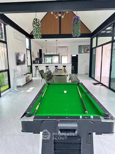 Luxurious open-plan living room with pool table and modern kitchen in a stylish home.